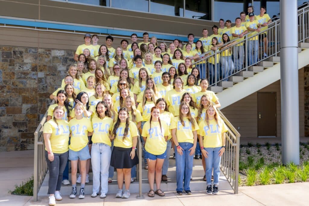 A large group of Rose State College PLC students pose on a staircase outside.