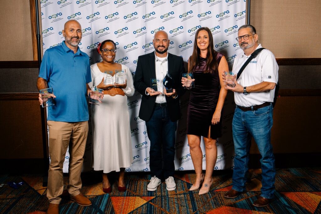 The Rose State College Marketing and Communications team poses with multiple OCPRA awards and the Best in Show trophy at the Oklahoma College Public Relations Association annual conference.